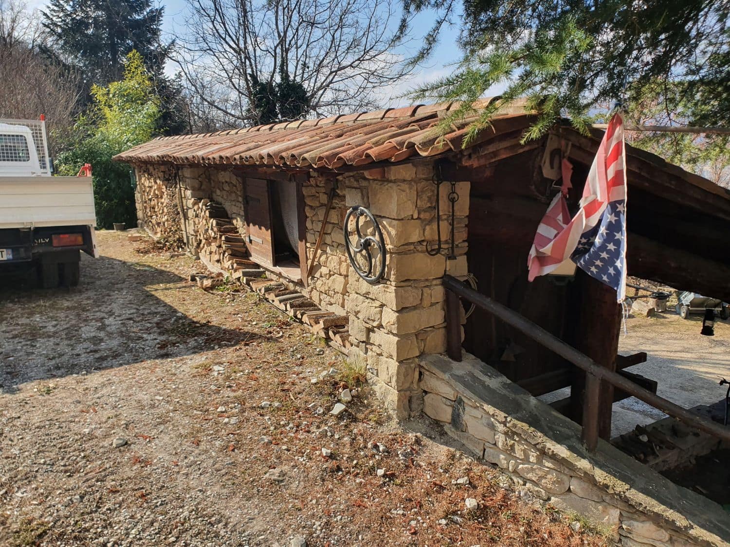 Long low stone building, old tile roof and timber lean-to.