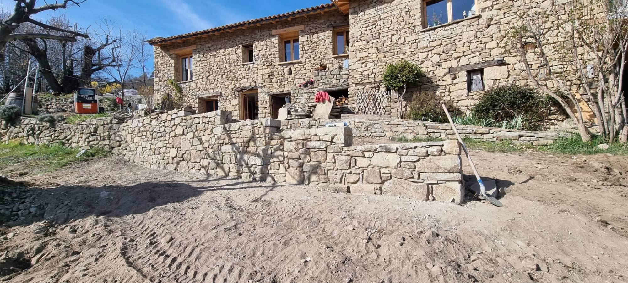 Stone house in a hamlet at Braux: dry-stone retaining walls and steps built in front of the house, ground still being worked.