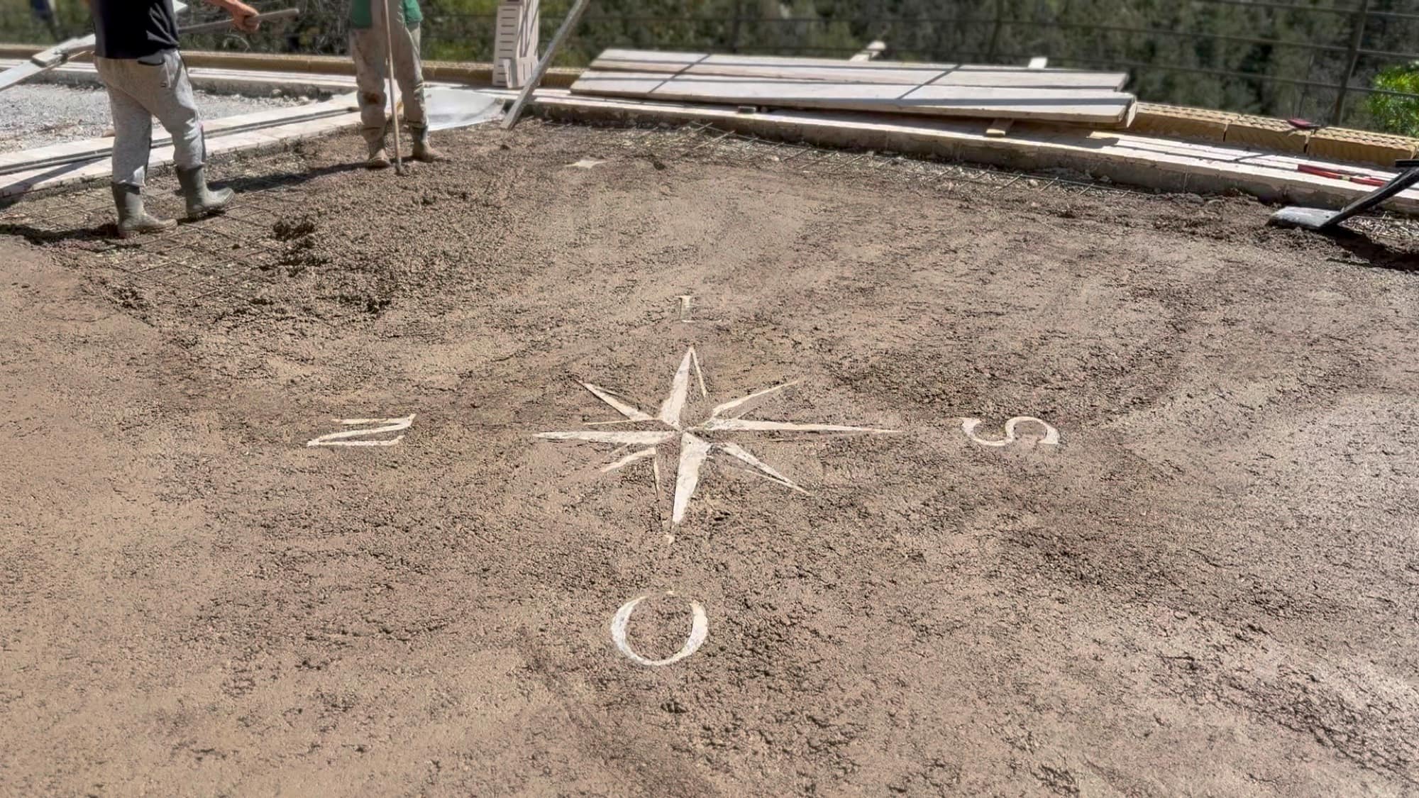 Compass rose traced by hand into the fresh concrete of the terrace.