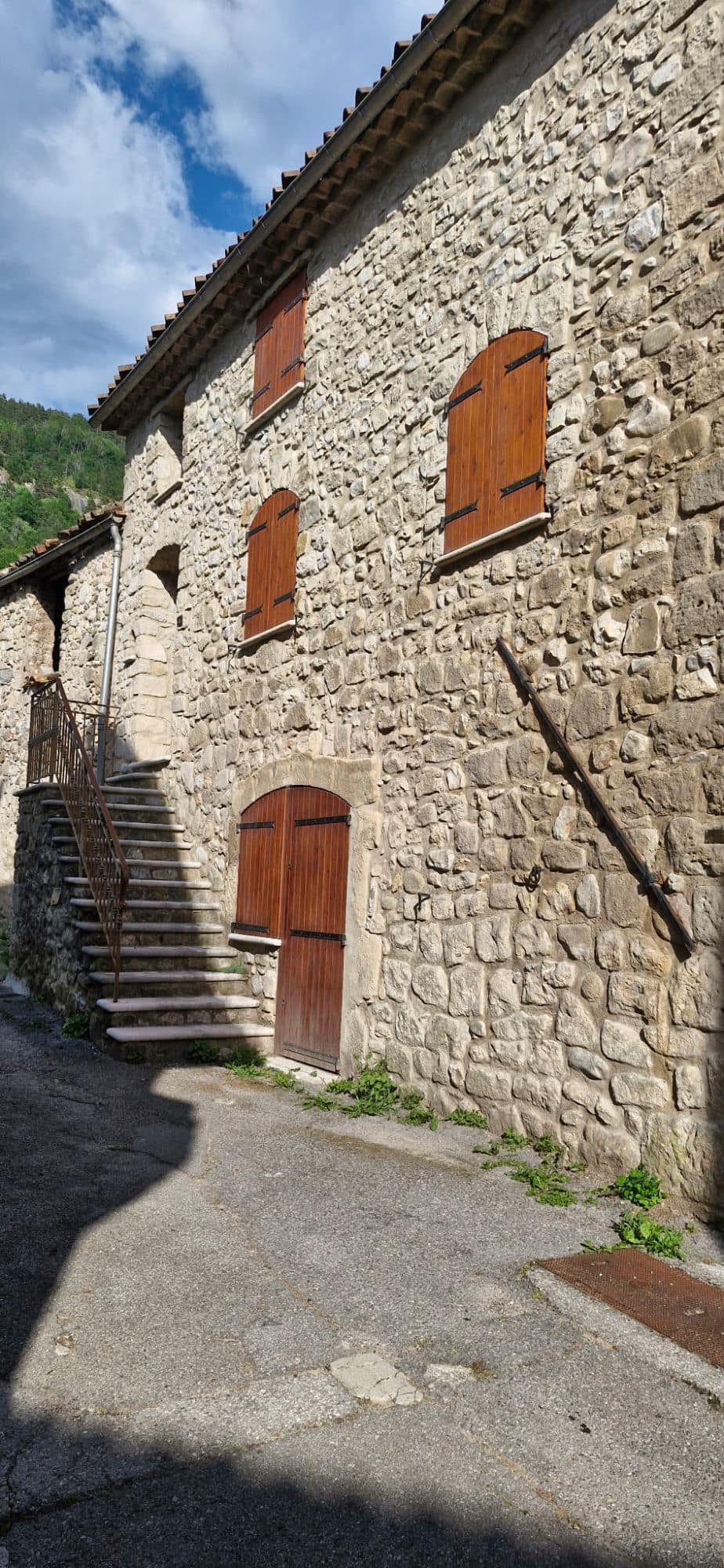 Village stone façade, arched doors and shutters, masonry outside stair.