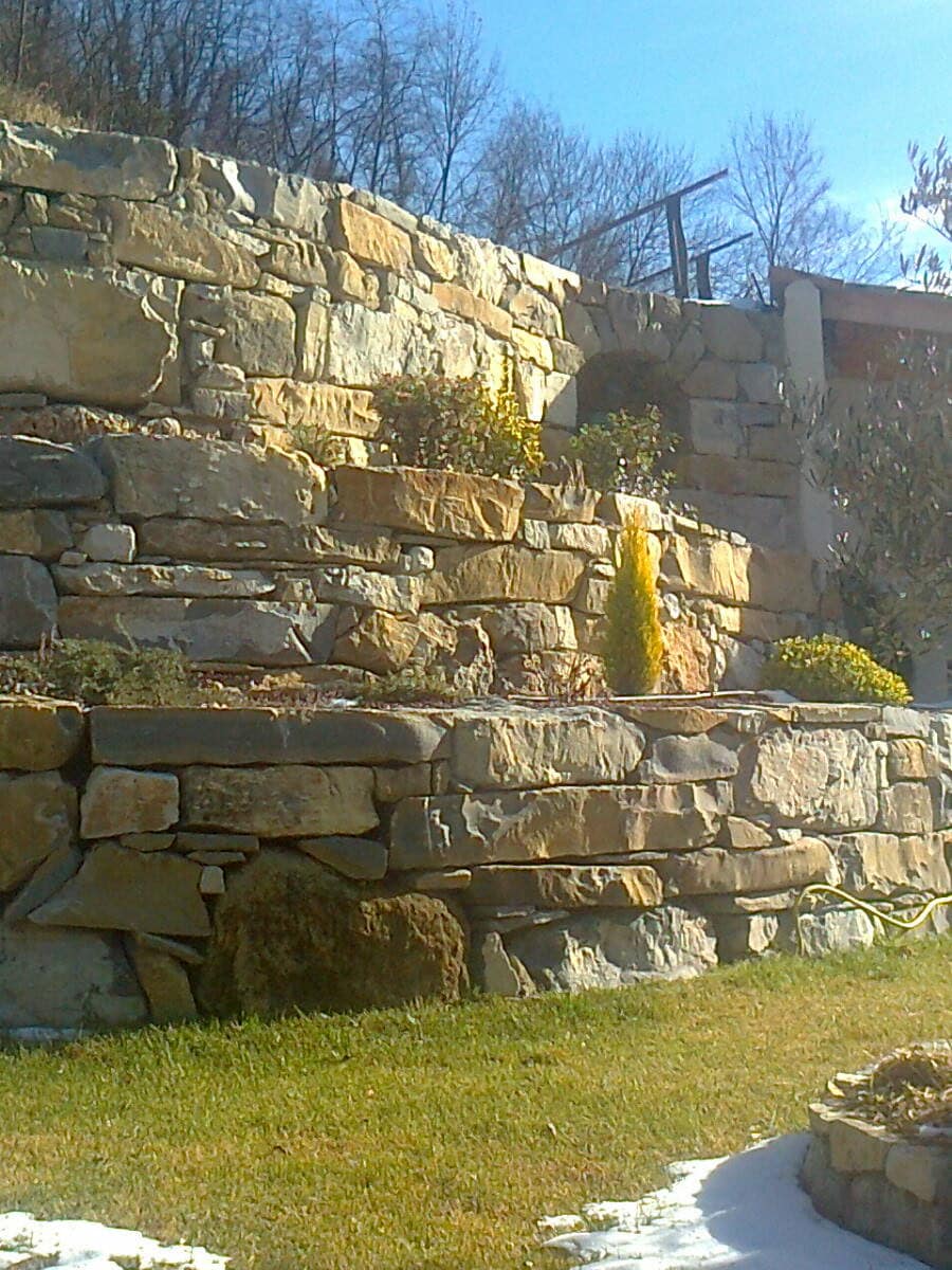 Stone retaining walls stepped over several levels, with planted terraces.