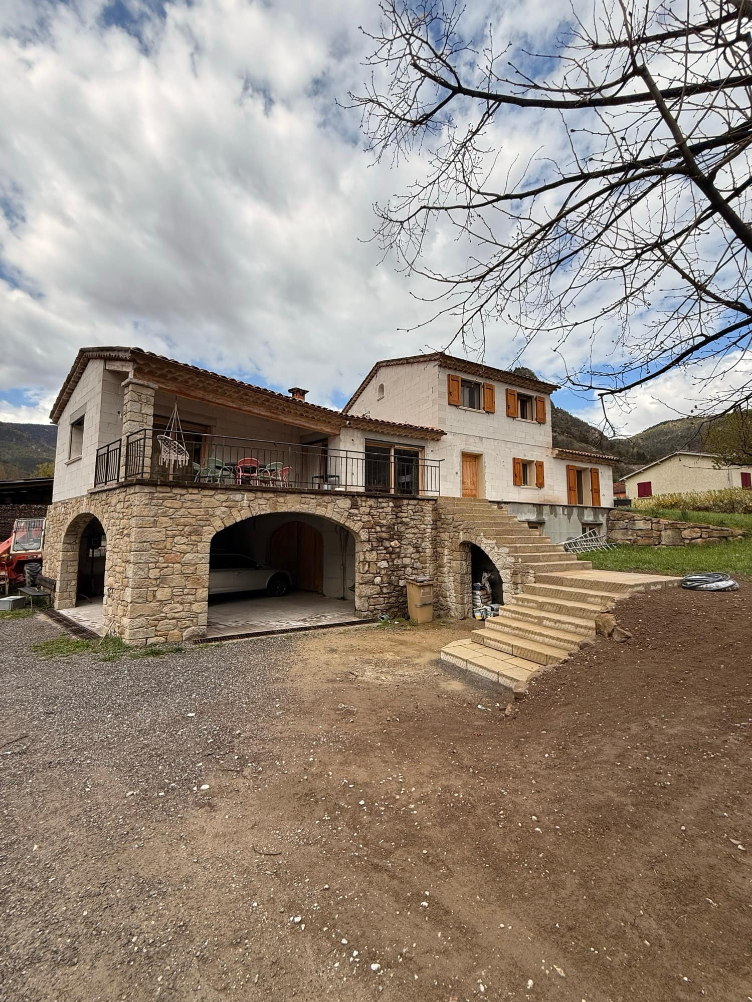 Outdoor steps and stone retaining wall in front of a village house, levelled platform in the foreground.