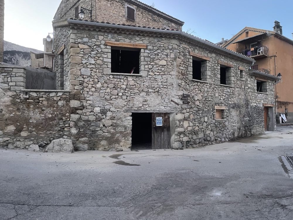Village house fully repointed in stone, with new timber lintels above the openings.