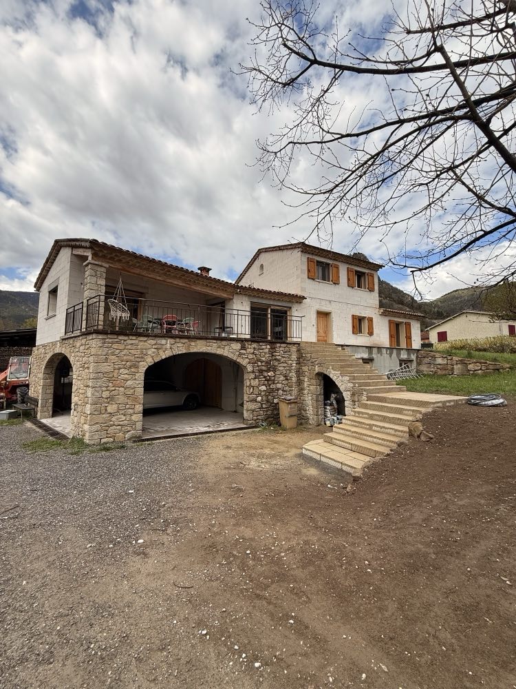 House whose terrace rests on three stone arches, with a masonry outdoor staircase.